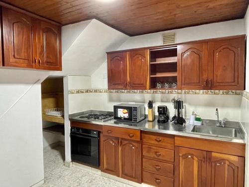 a kitchen with wooden cabinets and a stove top oven at New apart steps from CC Mayorca in Sabaneta