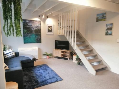 a living room with a staircase and a tv at Kiwiana Art apartment , near city and Queens Park in Invercargill