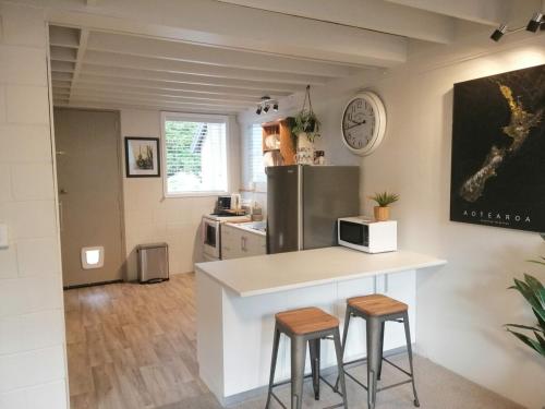 a kitchen with a counter with two stools and a microwave at Kiwiana Art apartment , near city and Queens Park in Invercargill