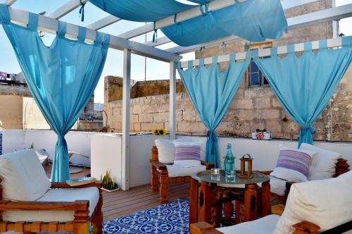 a patio with blue drapes and white furniture at Chapel 5 Boutique Suites B&B in Naxxar