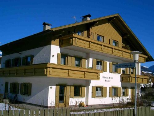 a large white building with a wooden roof at Appartments Hilber in Brunico