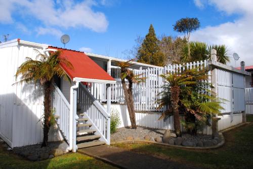 a white fence with a red roof and palm trees at Kings Ohakune in Ohakune