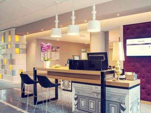 a lobby with a desk with chairs and a computer at Mercure Gdańsk Posejdon in Gdańsk
