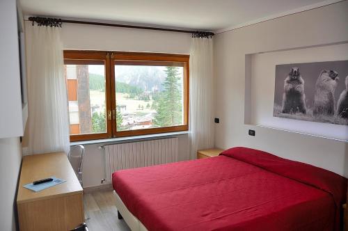a bedroom with a red bed and a window at Hotel Sud Ovest in Sestriere