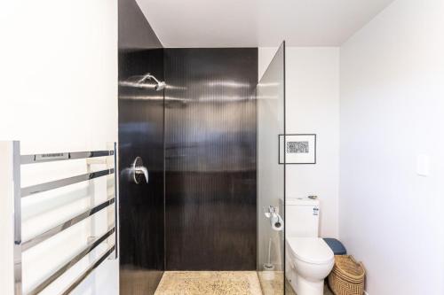 a bathroom with a toilet and a shower at The Black Barn - Karitane Beach in Karitane