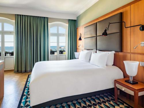 a large white bed in a room with windows at Sofitel Grand Sopot in Sopot