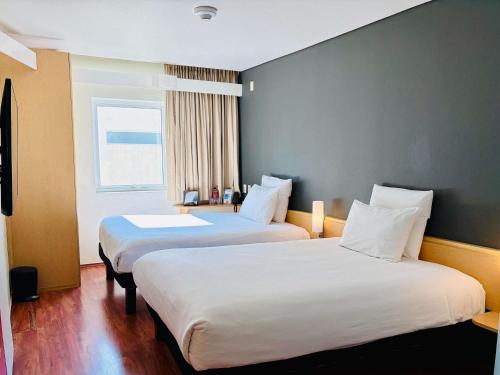 a hotel room with two beds and a window at Ibis Monterrey Valle in Monterrey