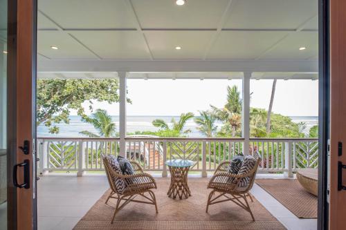 a porch with chairs and a table and the ocean at The Emerald Surf House I home in Waialua