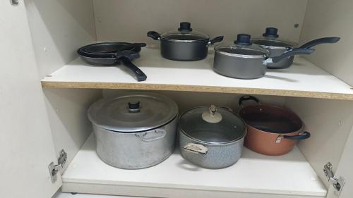a shelf with pots and pans in a kitchen at Alojamento in Caxias do Sul