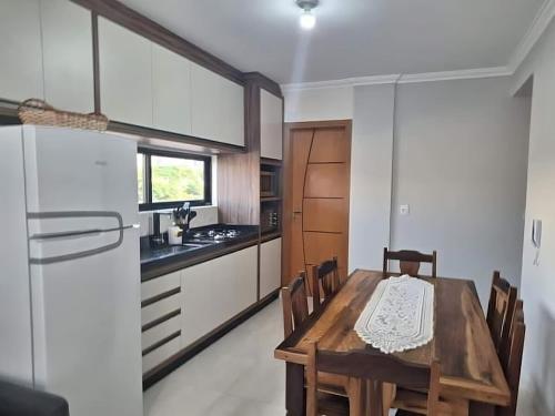 a kitchen with a wooden table and a dining room at Ap 440 m do mar, próx Beto Carrero in Navegantes