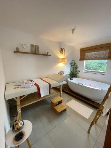 a bathroom with a tub and a bed and a sink at Quase um Spa in Petrópolis