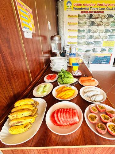 una mesa con platos de frutas y hortalizas. en Vangvieng Rock Backpacker Rooftop Hostel, en Vang Vieng