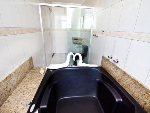 a bathroom with a black tub and a sink at Don Carlo Hotel in São Bernardo do Campo