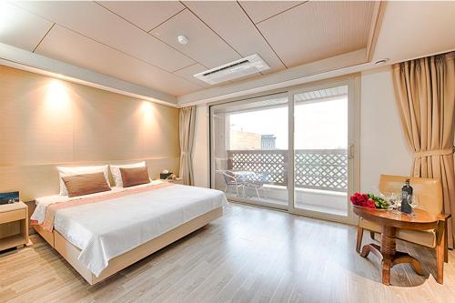 a bedroom with a large bed and a balcony at Andong Richell Hotel in Andong