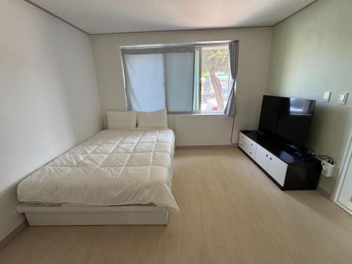 a bedroom with a bed and a flat screen tv at Gangneung Sandstay in Ŭmji-mal