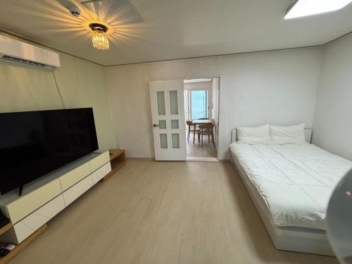a bedroom with a bed and a flat screen tv at Gangneung Sandstay in Ŭmji-mal