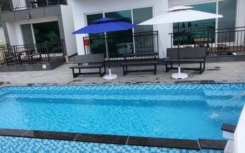 a pool with benches and umbrellas next to a building at Geoje View Pension in Geoje 
