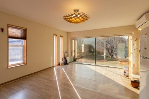 an empty living room with a large window and a chandelier at Hwasun Byeolsan Pension in Wajun