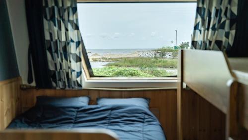 a bed in a room with a window at Gangneung Base Camp Caravan Glamping in Hwapyeong-dong