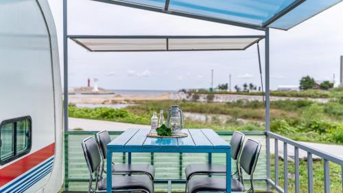 a table and chairs on a porch with a view of the ocean at Gangneung Base Camp Caravan Glamping in Hwapyeong-dong