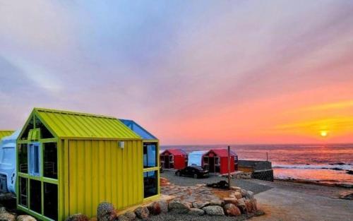 a yellow and red building on the beach with a sunset at Pohang Unis Sea Caravan Guryongpo Branch in Saegi