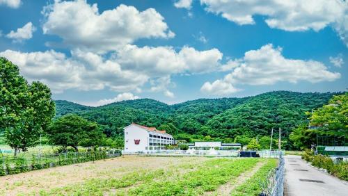 a building in a field with mountains in the background at Glamdog Dog Pension Tongyeong Branch in Wŏnmul-li
