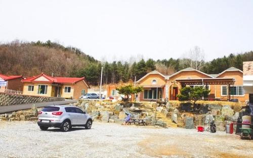a car parked in a parking lot in front of a house at Choongju Garden Arirang Pension in Chungju