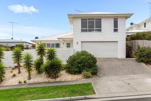 a white house with a garage and palm trees at 4BR Torquay Retreat with Serene Views in Torquay
