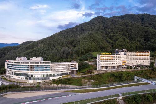 two large buildings in front of a mountain at Take Hotel & Resort Inje Speedium in Inje