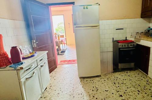 a kitchen with a refrigerator and an open door at Apartamento praia do farol in Mosqueiro