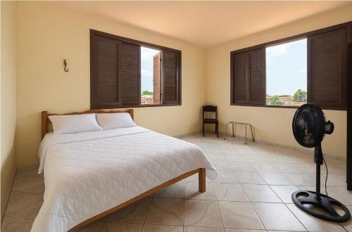 a bedroom with a white bed and two windows at Apartamento praia do farol in Mosqueiro