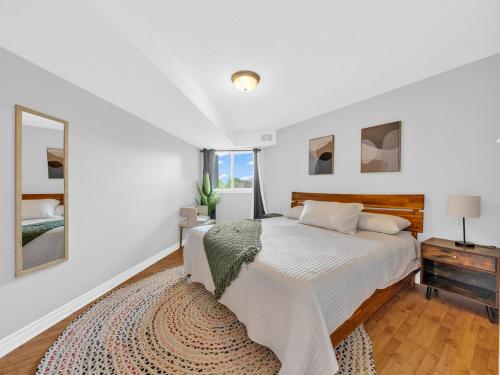 a white bedroom with a large bed and a mirror at Rare find by the Riverside in Windsor