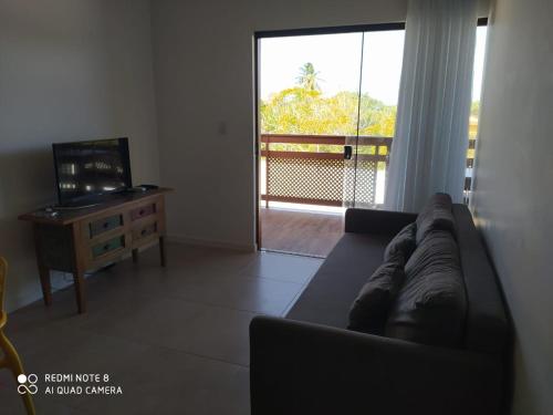 a living room with a couch and a large window at Reserva itacimirim, condomínio eco itacimirim in Camacari