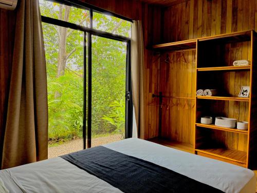 a bedroom with a bed and a large window at Cabaña Grande océan and jungle Infinity swim pool in Santa Teresa Beach