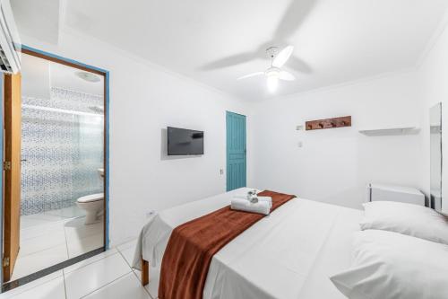 a white bedroom with a bed and a bathroom at Pousada Maré Cheia in Paraty