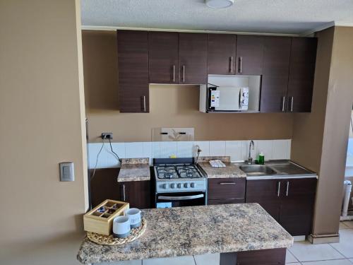 a kitchen with wooden cabinets and a stove top oven at Departamento en Talca con 3D-2B y estacionamiento in Talca