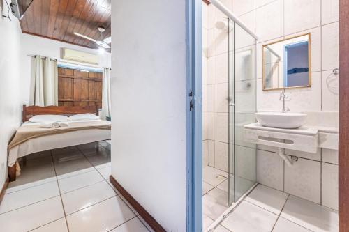 a bathroom with a shower and a sink and a bed at Pousada Maré Cheia in Paraty