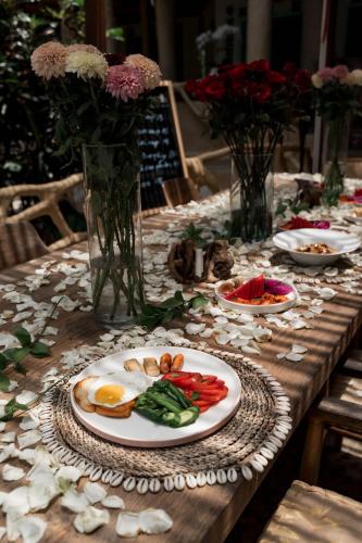 a long wooden table with plates of food and flowers at Sacred Mandala retreat center Ubud in Ubud