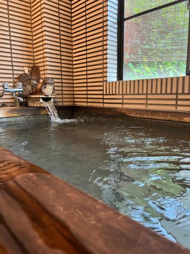- une piscine avec une fontaine dans une chambre dans l'établissement 民話の宿荒澤屋旅館, à Okutama