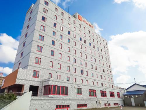 a tall white building with red windows at KOKO STAY Chitose - formerly Hotel Wing International Chitose in Chitose