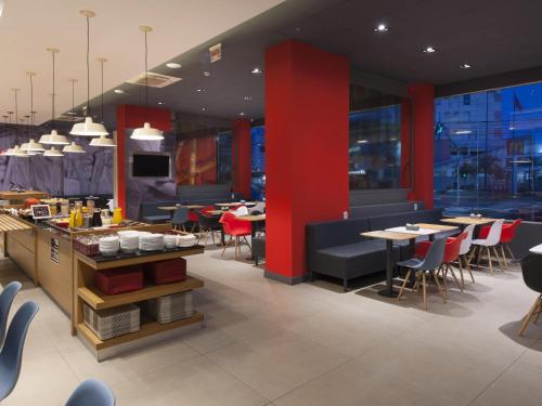 a restaurant with red walls and tables and chairs at ibis Navegantes Itajai in Itajaí