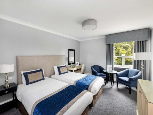 a hotel room with two beds and a desk and chair at Mercure Manchester Norton Grange Hotel & Spa in Rochdale