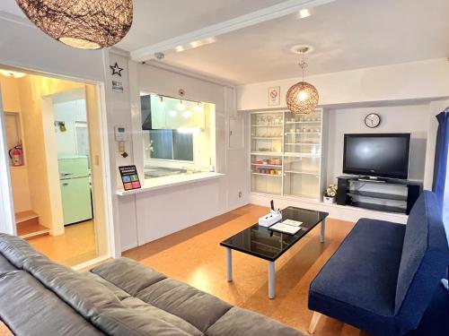 a living room with a couch and a tv at ハレアカラ - 4階建てプライベートマンション in Asato