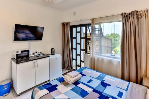 a bedroom with a bed and a tv and a window at Rembrandt in Ballito