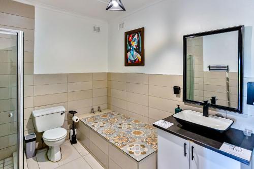 a bathroom with a toilet and a sink and a mirror at Rembrandt in Ballito