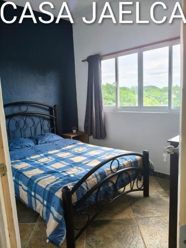 a bedroom with a bed with a blue and white comforter at spacious apartment with ocean view in Brisas de Zicatela
