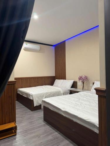 Hồ Bình Yên Homestay&Coffee-BBQ في Plei Kơtêng: غرفة بها سريرين وخط أزرق على الحائط