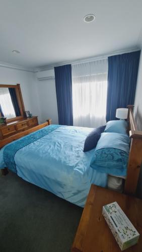 une chambre avec un lit avec des draps et des oreillers bleus dans l'établissement Scenic Coastal Gem with Pool, Tennis, Securely Gated, à Whangaparaoa