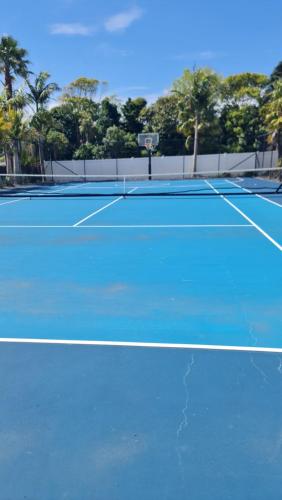 a tennis court with a blue court at Scenic Coastal Gem with Pool, Tennis, Securely Gated in Whangaparaoa