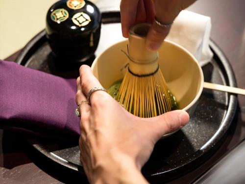 a person is whisking food in a bowl with a brush at HANARE by Tokyu Stay Kyoto Sanjo in Kyoto